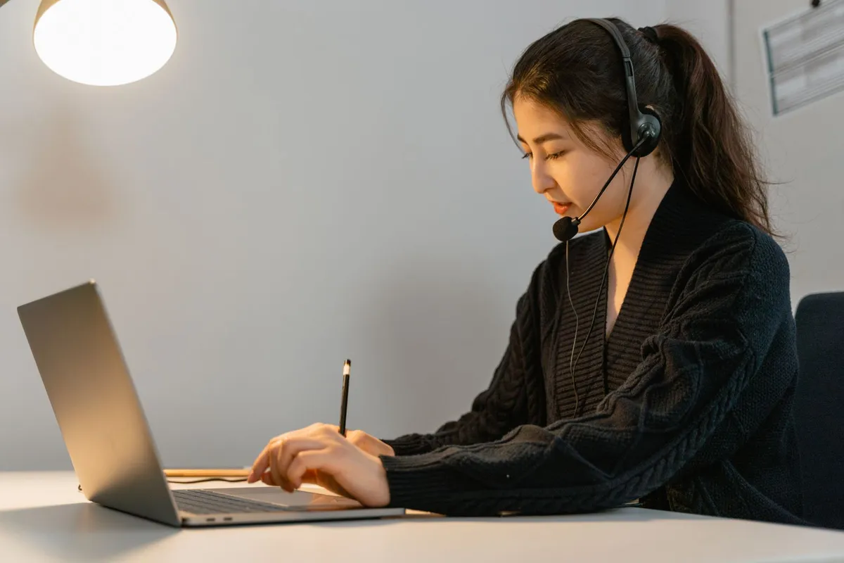 パソコンの横でメモを取る人のイメージ