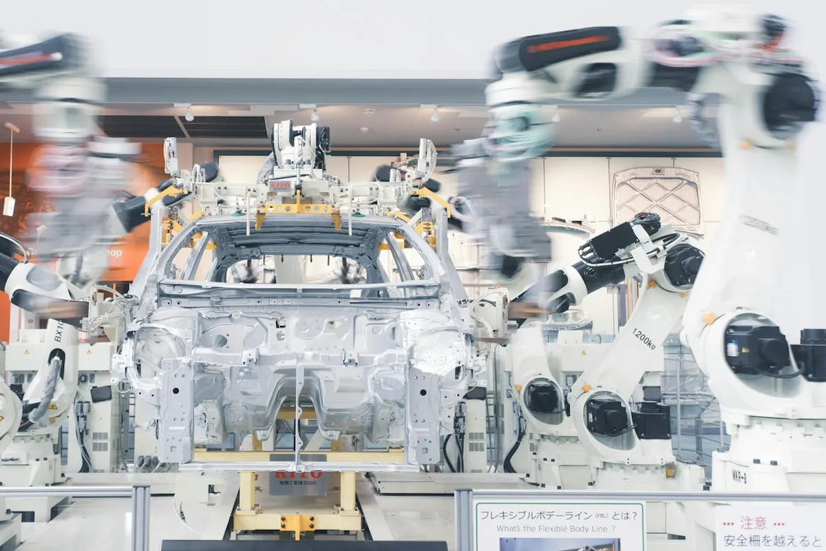 自動車の車体を組み立てる複数のロボットアームのイメージ