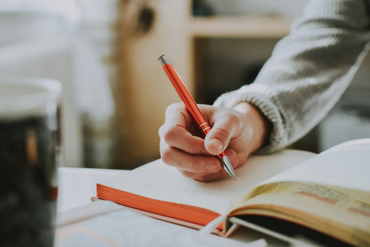ノートにペンで書き込む手元。学習のイメージ