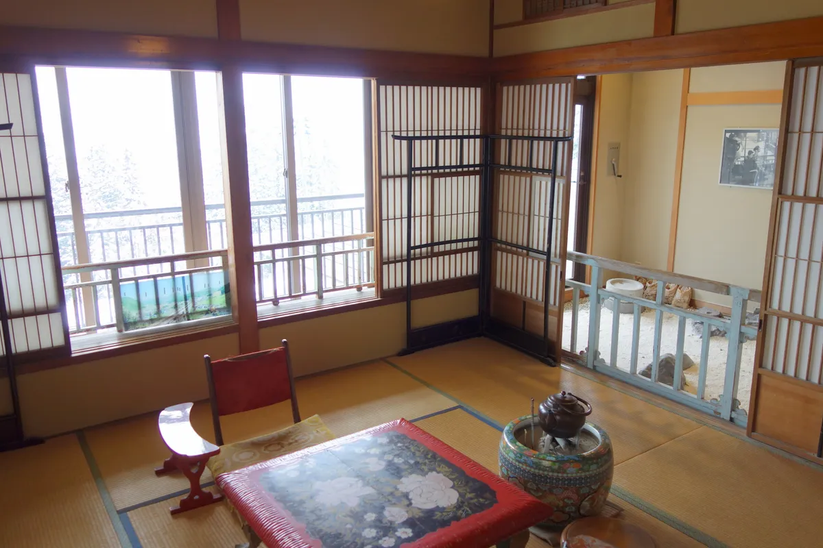 畳と窓辺の椅子がある旅館客室のイメージ写真