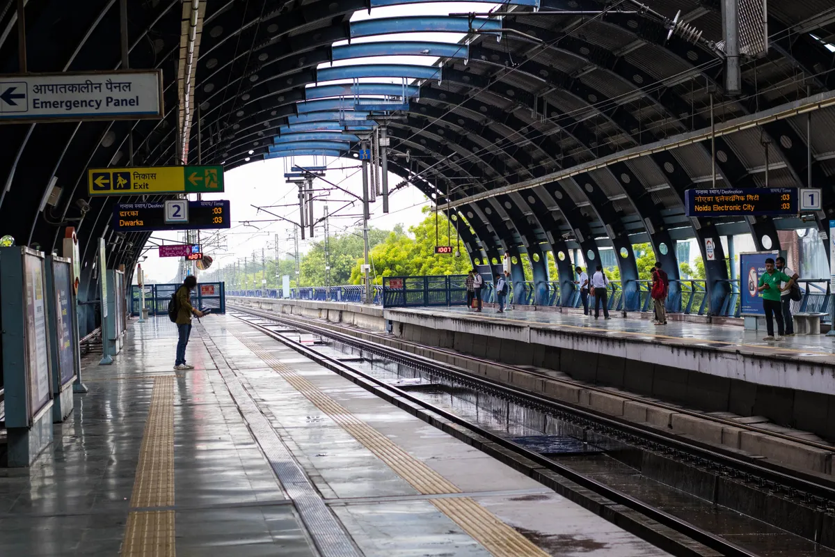 雨の日のニューデリー地下鉄駅で電車を待つ利用者
