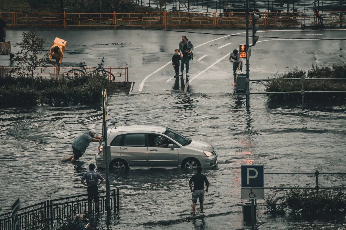 冠水した市街地で車を押す人々のイメージ写真